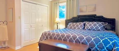 A bedroom with a bed, a ceiling fan, a nightstand, a lamp, and a door.