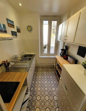 Une cuisine de taille réduite, équipée d’une cuisinière, d’un évier et d’une fenêtre.