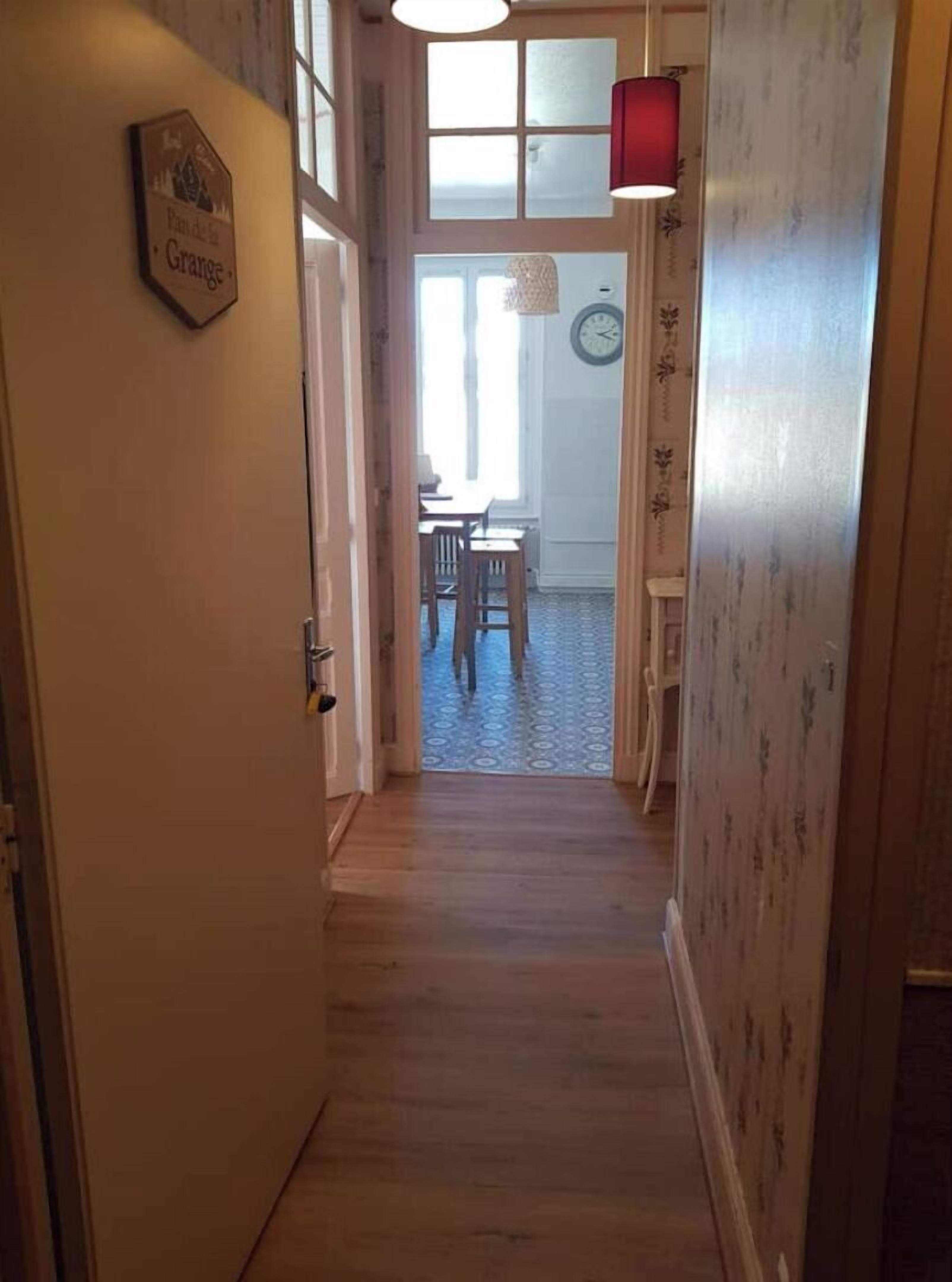 Un pasillo estrecho con piso de madera que lleva a un comedor con una mesa y sillas.