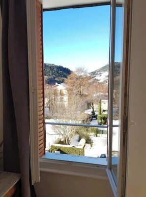 Et værelse med et stort vindue, der giver udsigt over et sneklædt landskab og en bygning i det fjerne.