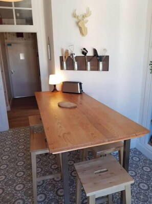 Et træbord med bænk, en brødrister og et monteret dådyrskranium på væggen.