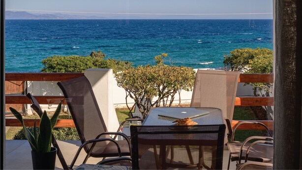 A balcony with a table and chairs overlooking the sea. - Nami Villa Beach Front Airport by Airstay (Spata-Artemida)