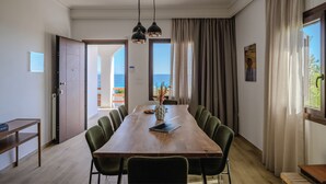 A dining area with a wooden table, green chairs, a laptop, and a vase with dried plants. - Nami Villa Beach Front Airport by Airstay (Spata-Artemida)