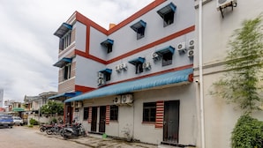 Un immeuble à plusieurs étages, doté d’une façade rouge et blanche, de climatiseurs et d’un auvent bleu.