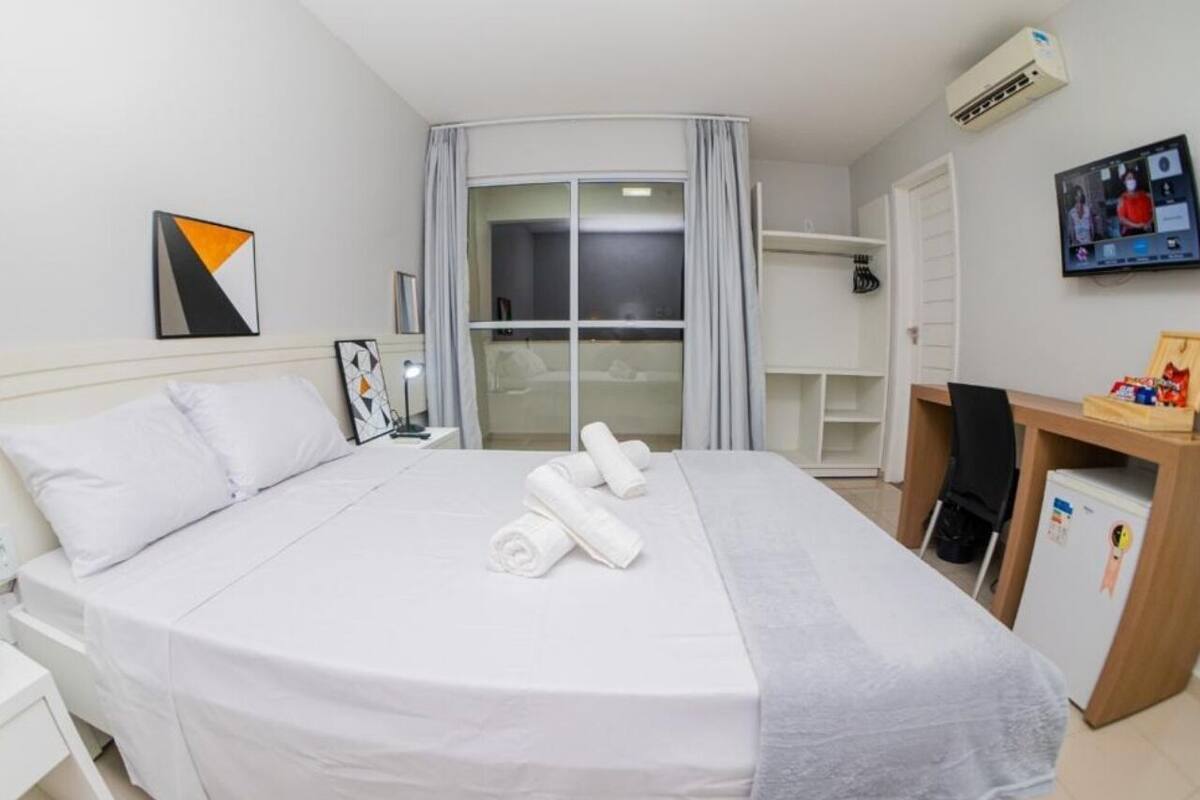 Ein Hotelzimmer mit Bett, Schreibtisch, Stuhl, Fernseher und einem Fenster mit Vorhängen.