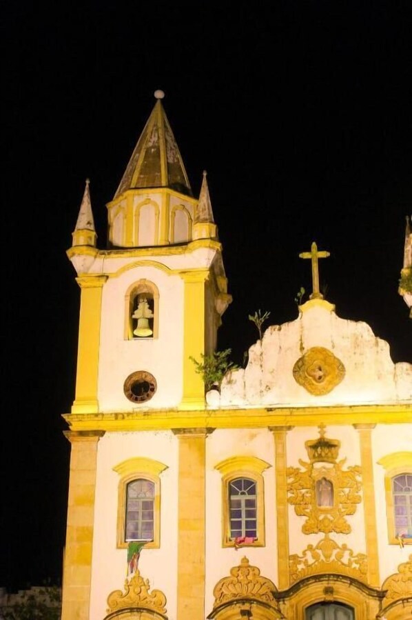 Um edifício histórico com uma torre de sino, janelas em arco e detalhes arquitetônicos elaborados.