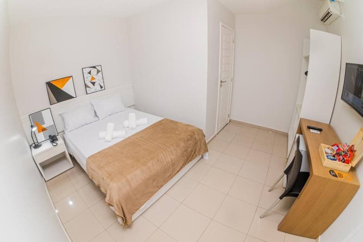 Ein Hotelzimmer mit Bett, Schreibtisch, Stuhl, Fernseher und einer Tür.