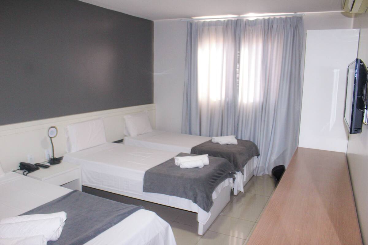 Ein Hotelzimmer mit zwei Betten, einem Schreibtisch und einem Fernseher.