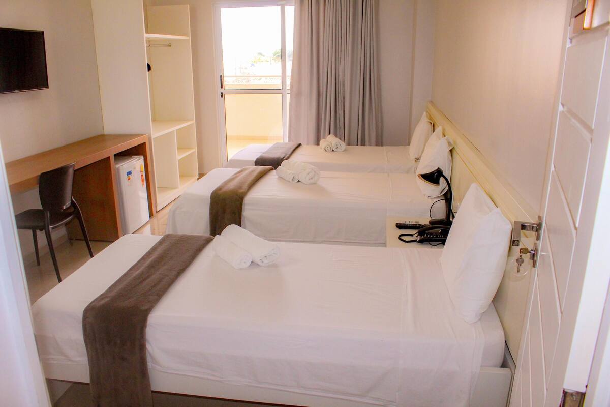 Ein Hotelzimmer mit zwei Betten, einem Schreibtisch, einem Stuhl und einem Fernseher.