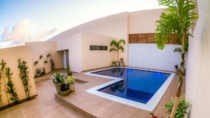 A modern outdoor pool area with tiled flooring, a rectangular pool, and various potted plants. - HOTEL ROCHEDO (Penedo)