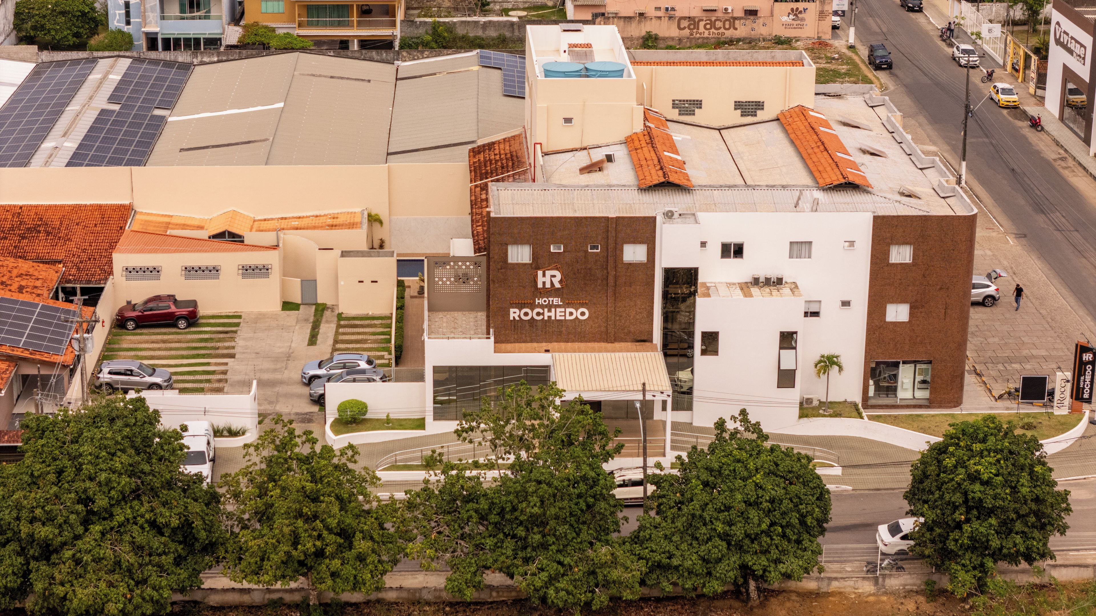 A hotel with a rooftop terrace, a parking area, and a street view.