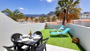 A rooftop terrace with a dining table set for two, two lounge chairs, and a small table with a bottle and glasses. - Lovely apartment Costa Adeje & Big Terrace (Costa Adeje)