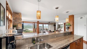 Une cuisine moderne dotée de plans de travail en granit, d’appareils électroménagers en acier inoxydable et d’un grand îlot central avec un évier.
