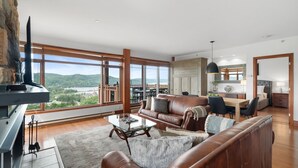 Un salon spacieux doté d’une grande fenêtre offrant une vue panoramique, d’un coin salon confortable et d’un espace repas.