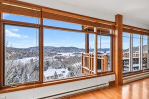 A room with large windows offering a view of a snowy landscape and a distant building.