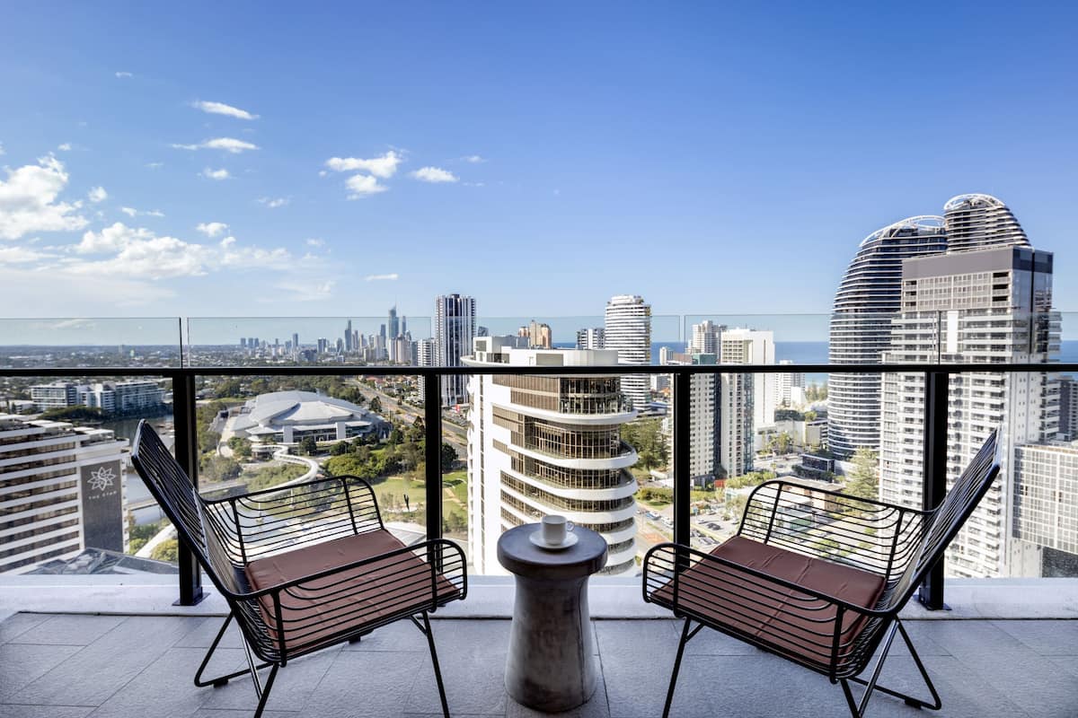 A balcony with two chairs and a table, offering a city view.