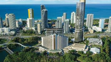 Un hotel de gran altura con una fachada curva distintiva, situado cerca de una masa de agua y rodeado de otros edificios.