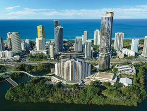 Un hotel de gran altura con una fachada curva distintiva, situado cerca de una masa de agua y rodeado de otros edificios.