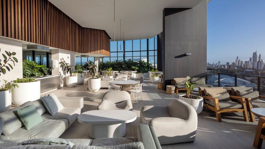 A rooftop lounge with seating, tables, and potted plants.