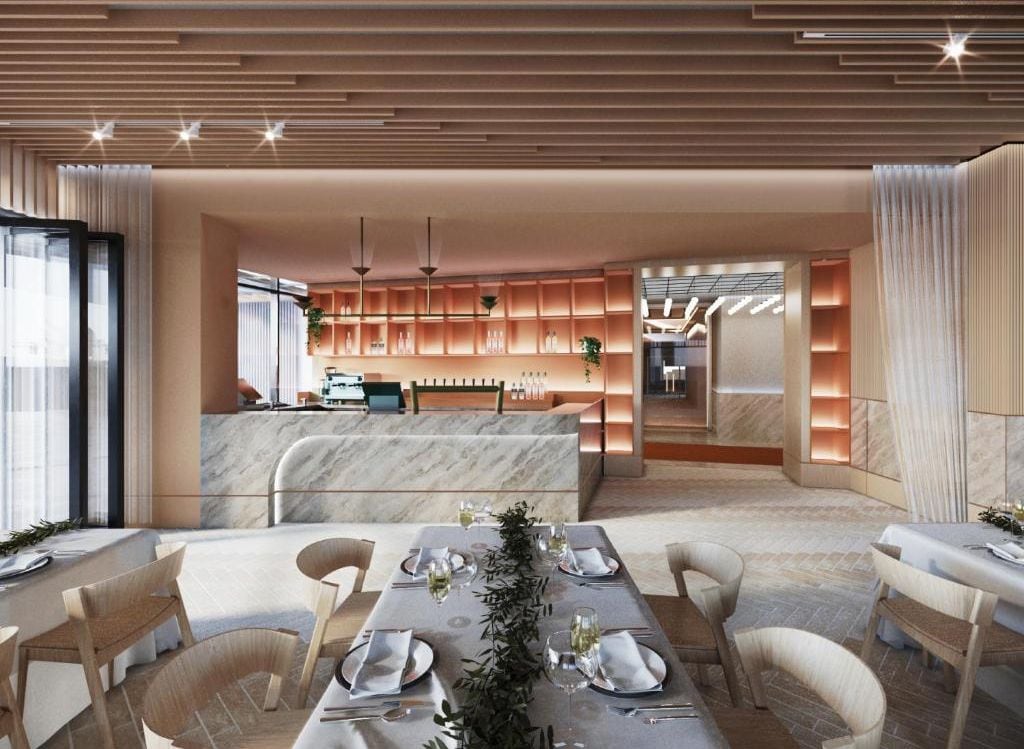 A modern dining area with a marble table, wooden chairs, and a kitchen in the background.