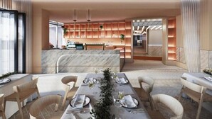 A modern dining area with a marble table, wooden chairs, and a kitchen in the background.