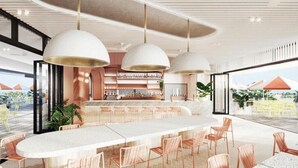 A modern bar area with a long counter, multiple hanging pendant lights, and a view of the outdoors.