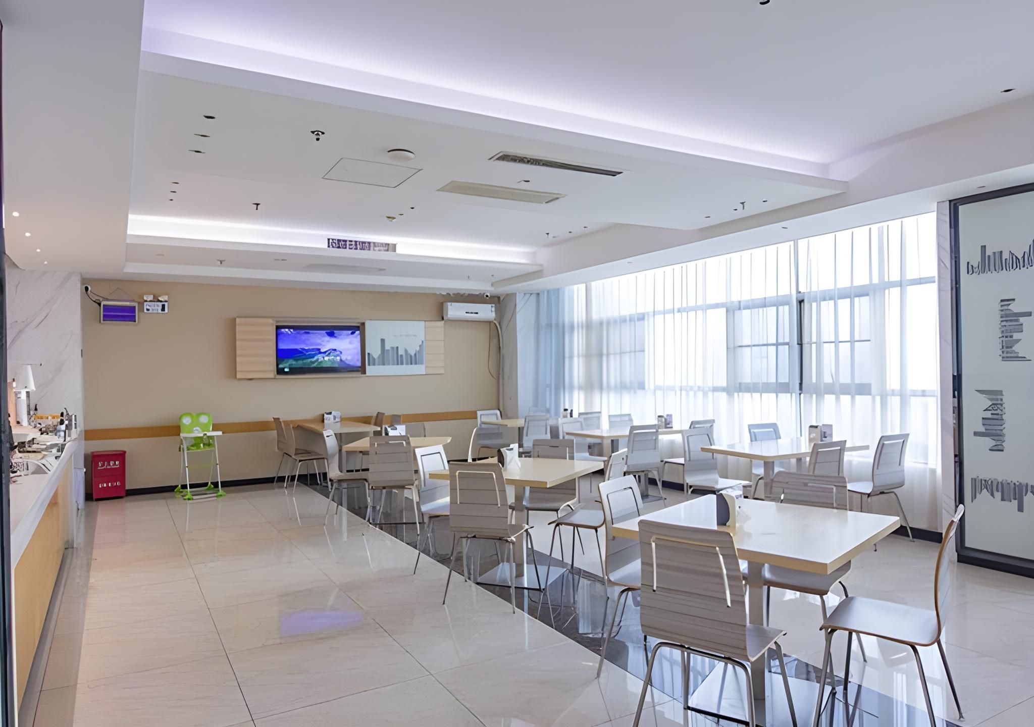 A modern conference room with tables and chairs, a television, and a large window.
