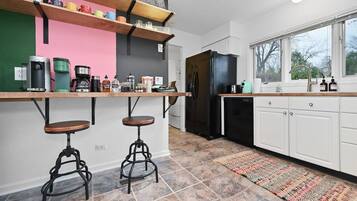 Una cocina moderna con un refrigerador negro, armarios blancos y una alfombra colorida.