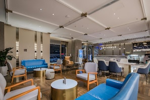 Un área de lounge moderna con asientos, una barra y vistas a la calle.