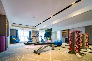 Un gimnasio con equipo de ejercicio, una cinta de correr y una pared con círculos como blancos.