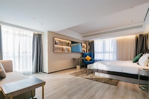 Una habitación de hotel moderna con cama, escritorio, silla y televisor.