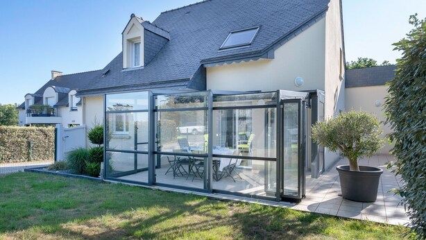 A modern house with a glass conservatory, a dining area, and a potted tree. - House for 8 - Pool - 950m from the sea (Saint-Gildas-de-Rhuys)