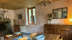 Un coin repas avec une table en bois, des chaises, une cheminée et un miroir au-dessus du comptoir.