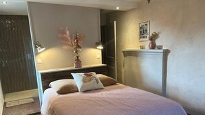 Une chambre à coucher avec un lit, des lampes de chevet, un miroir, une cheminée et un tableau accroché au mur.