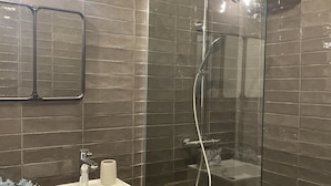 Une salle de bain avec une douche à parois de verre, un lavabo blanc et une table en bois.