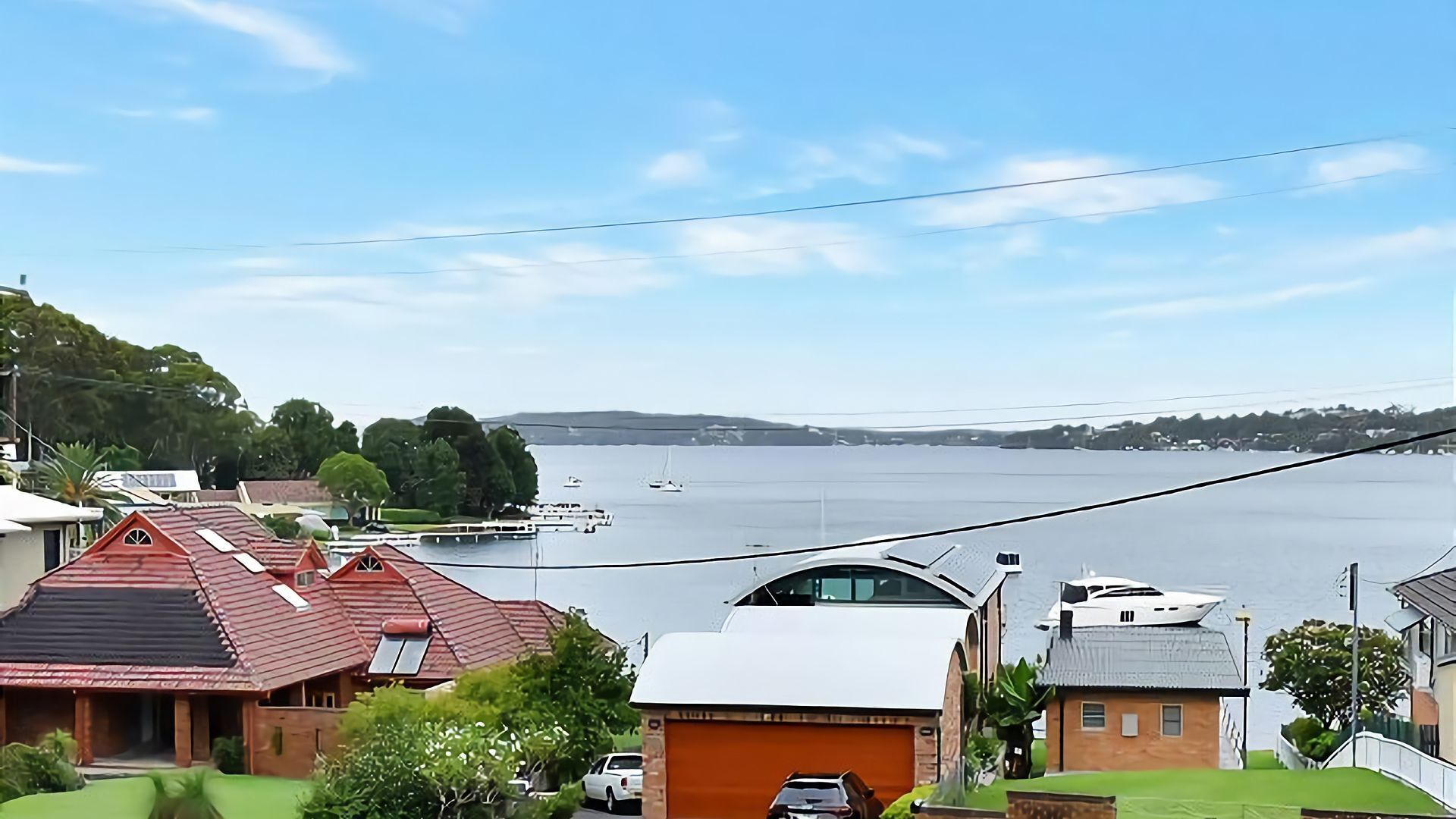 A residential area with houses, a large body of water, and a clear sky.