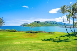 A golf course with a view of the ocean and mountains.