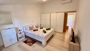 A bedroom with a bed, nightstand, dresser, and a TV stand. - Holiday apartment in Pula, big roof balcony and garden, pet friendly (Pula)