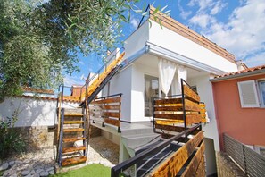 Une maison à deux étages avec un escalier en bois menant à un balcon.