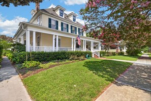 A two-story house with a front porch, a flag, and a well-maintained lawn. - Tazewell House Estate with Wraparound Porch (CAPE CHARLES)