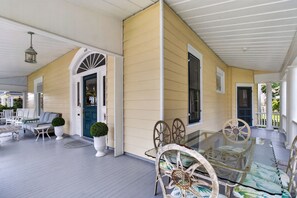 A covered porch with a glass table and chairs, a blue door, and a white railing. - Tazewell House Estate with Wraparound Porch (CAPE CHARLES)