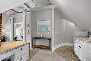 A modern kitchen with a wooden countertop, white cabinets, and a view of the ocean through a window. - Tazewell House Estate with Wraparound Porch (CAPE CHARLES)
