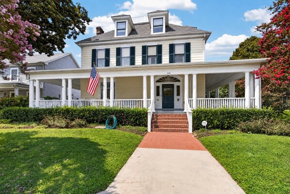 A two-story house with a front porch, a flag, and a well-maintained lawn. - Tazewell House Estate with Wraparound Porch (CAPE CHARLES)