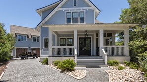 A two-story house with a front porch, a driveway, and a golf cart parked outside. - Dog Friendly with Pool and Golf Cart (Watersound)