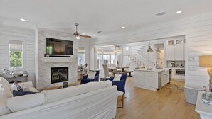 A spacious living area with a fireplace, a dining area, and a kitchen with white cabinetry. - Dog Friendly with Pool and Golf Cart (Watersound)