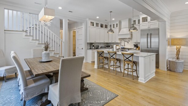 A spacious kitchen with white cabinetry, a central island with bar stools, and a modern pendant light fixture. - Dog Friendly with Pool and Golf Cart (Watersound)