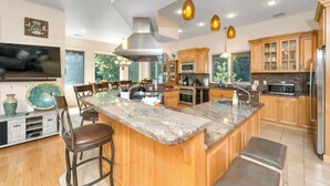 Una cocina moderna con una isla grande, armarios de madera, electrodomésticos de acero inoxidable e iluminación colgante.