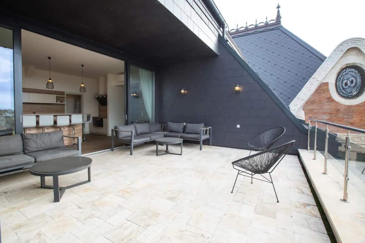 A modern outdoor living area with a sofa set, a round table, and a chair.
