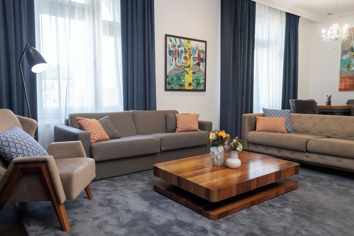 A modern living room with a sofa set, a coffee table, and a painting on the wall.