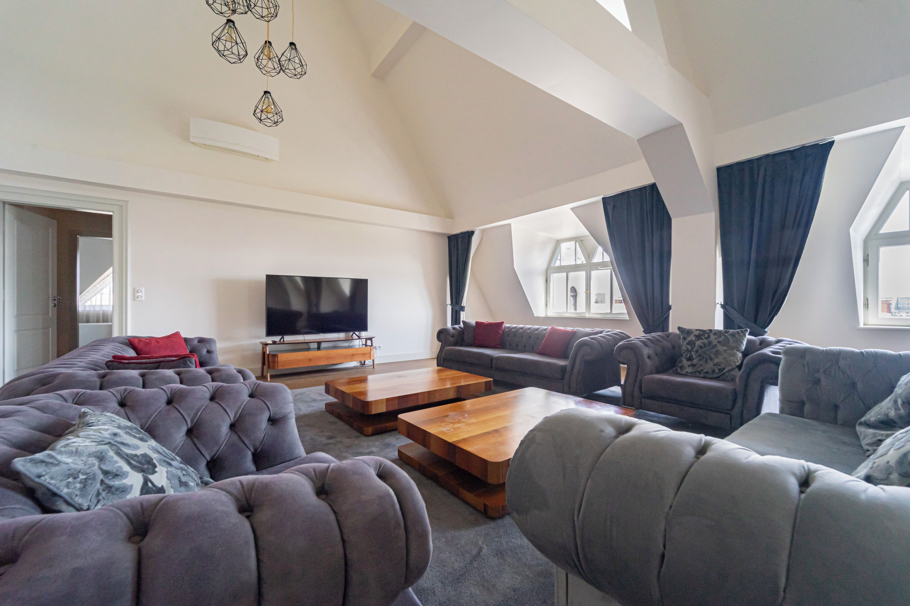 A modern living room with a large sectional sofa, a flat-screen TV, and a wooden coffee table.